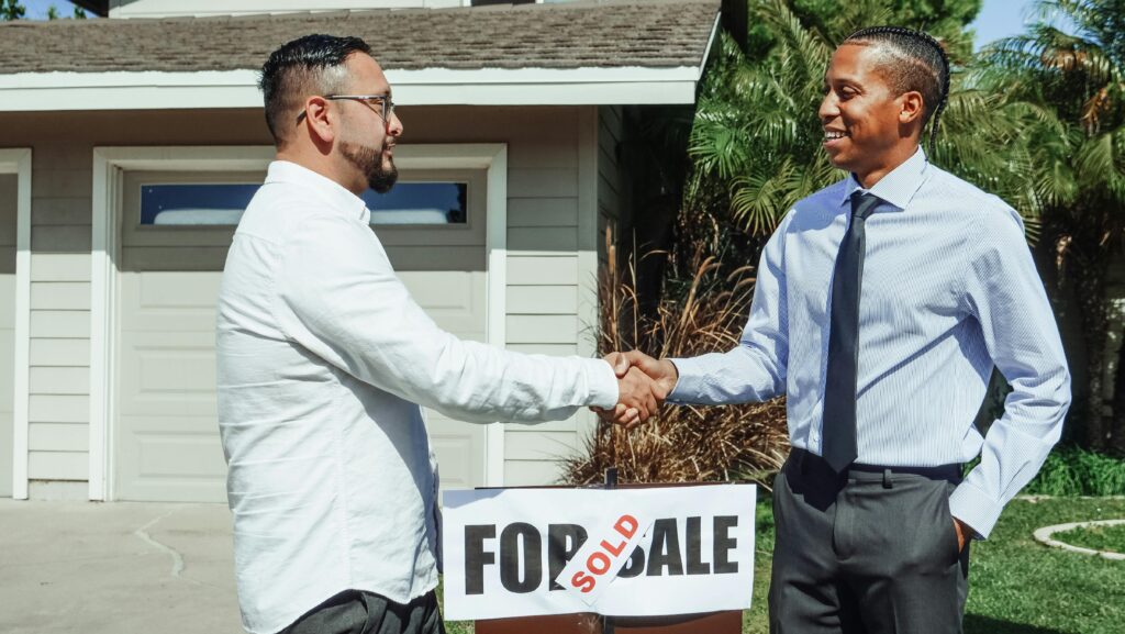 Photo of people standing in front of a Sold sign 